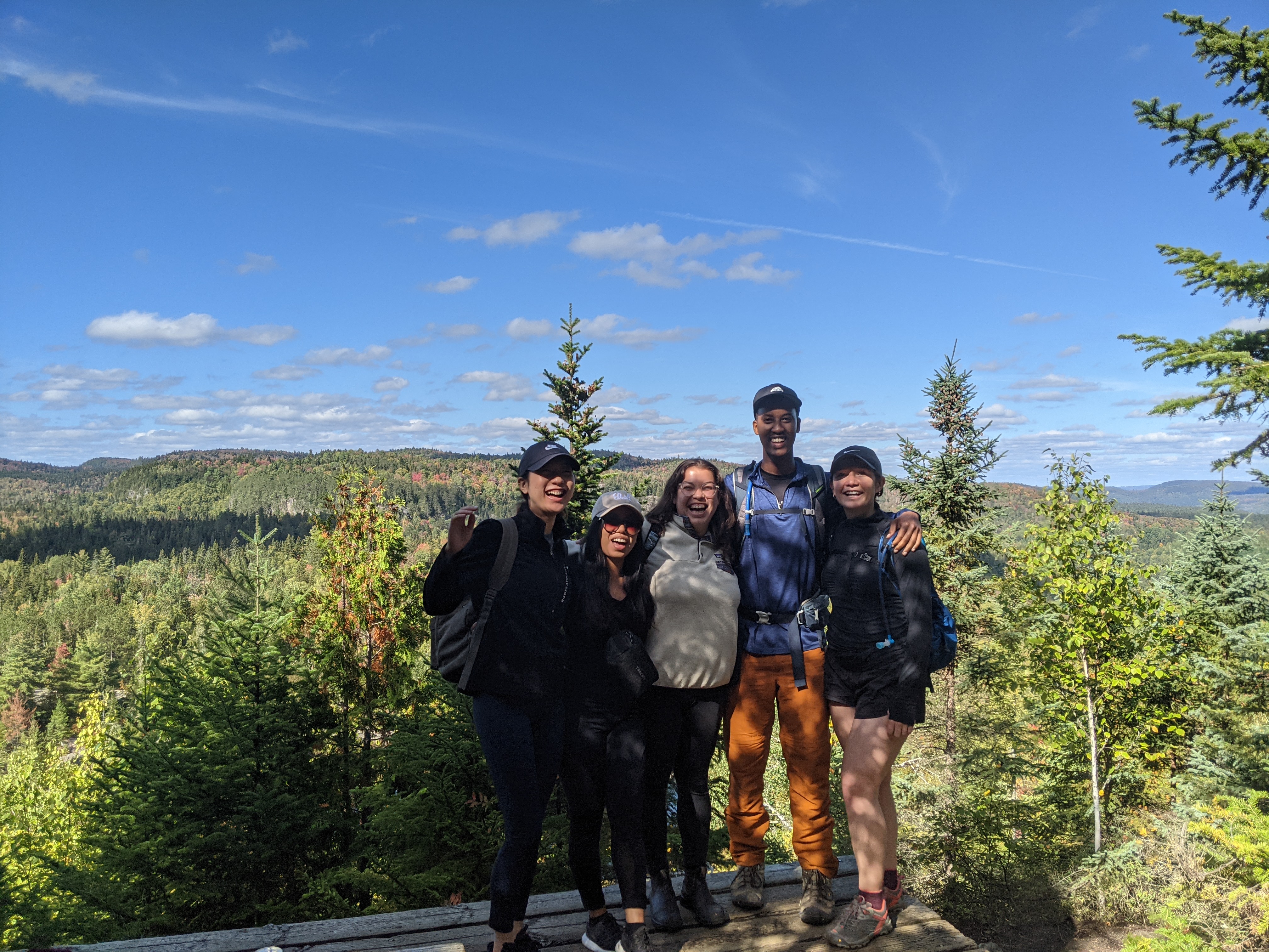 A group of 5 friends posing at the top of a mountain