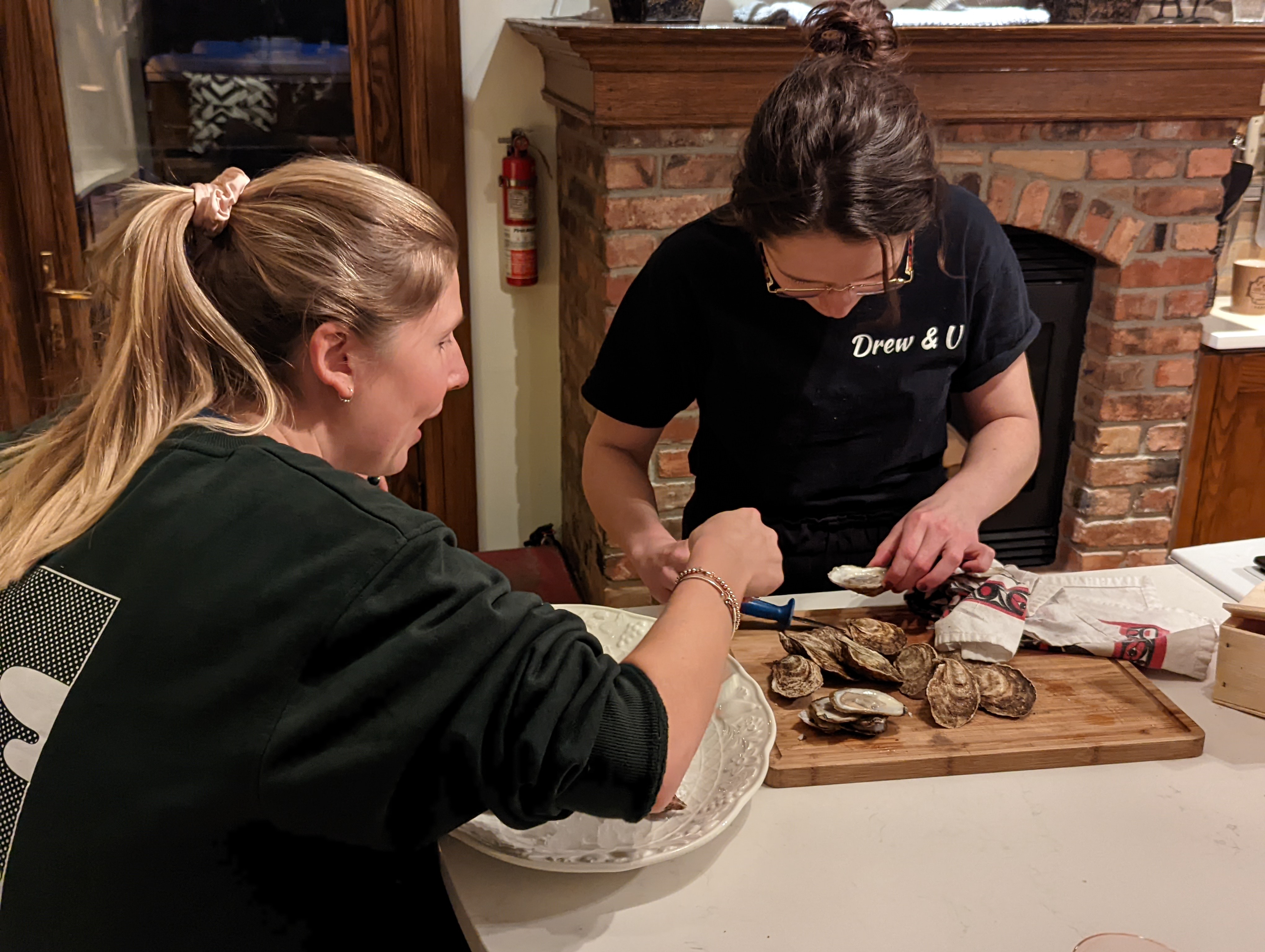 A pair of friends helping one another chuck oysters in preperation for dinner